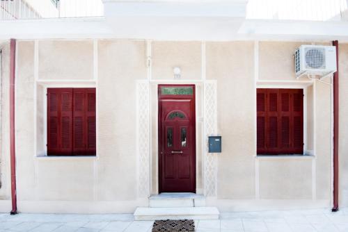 a red door on a white building with red shutters at Best House, Marina Home, Athens Avenue, Patra in Patra