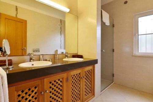 La salle de bains est pourvue de 2 lavabos et d'un grand miroir. dans l'établissement Villa Varandas Do Lago - 5 Bedroom villa - Stunning pool area - Table tennis, à Vale do Lobo