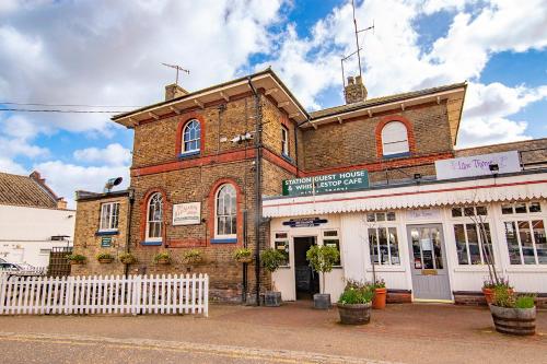 um edifício de tijolos com uma cerca branca em frente em The Station Guest House em Woodbridge