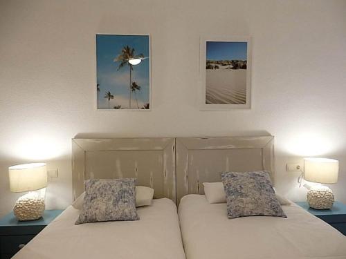 dwa łóżka w sypialni z dwoma lampami i obrazami na ścianie w obiekcie Bleu Mare Apartment w mieście Torremolinos