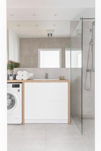 a bathroom with a sink and a washing machine at Kamienica Parkowa in Dąbki