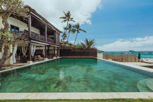 a swimming pool in front of a house with the ocean at The Village of Angels in Manggis