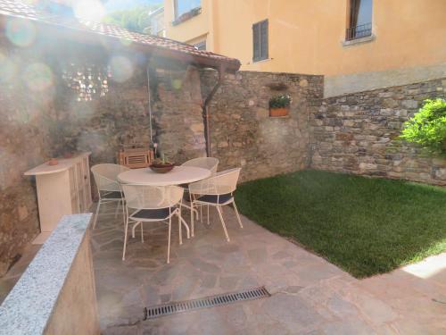 a patio with a table and chairs and grass at Appartamenti Il Castellaccio in San Siro