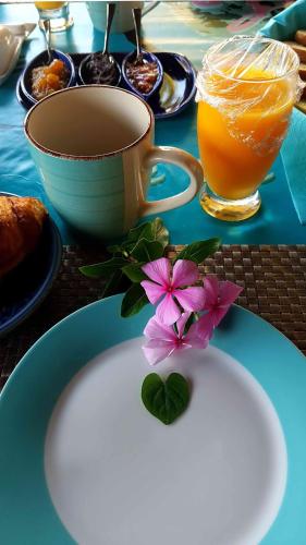 a plate with a flower and a cup of orange juice at La Maison des Hôtes in Saint-Joseph