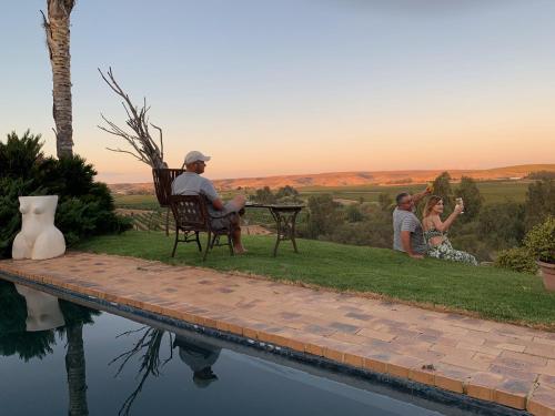 a group of people sitting around a table by a pool at Melkboomsdrift Guest House & Conference Centre in Vredendal