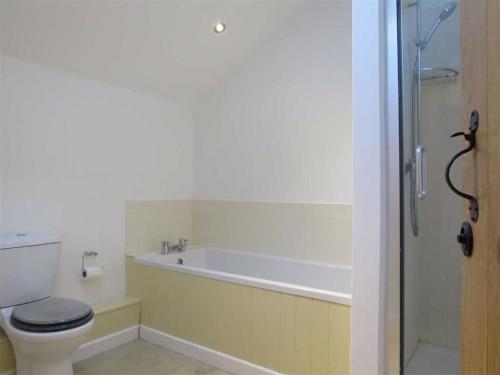 a bathroom with a tub and a toilet and a shower at Baptist Cottage in Cheverell