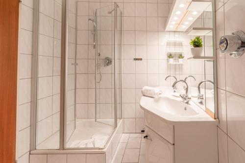 ein weißes Badezimmer mit Dusche und Waschbecken in der Unterkunft Alpenglöckchen in Sonthofen