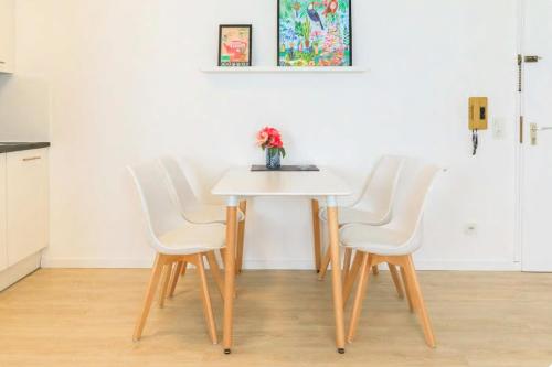 a table with four white chairs and a vase on it at Modern Apartment in city center in Würzburg