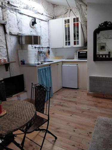 une cuisine avec des armoires blanches et une table et des chaises dans l'établissement Le grenier, 3eme étage sans ascenseur, à Condom