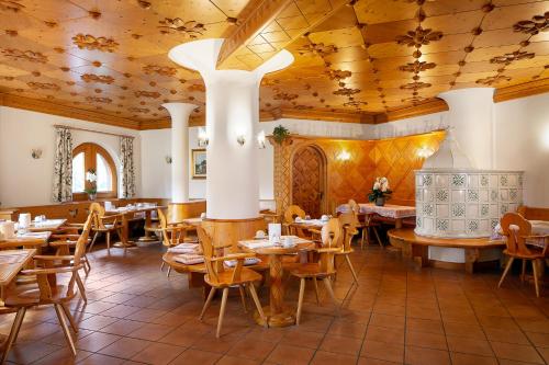 a restaurant with wooden ceilings and tables and chairs at Hotel Natale in Cortina dʼAmpezzo