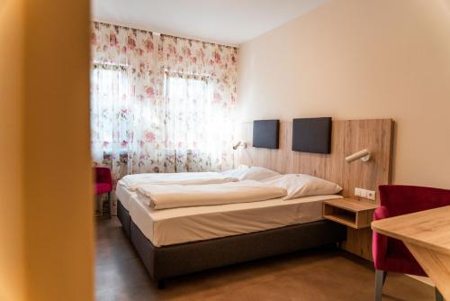 a bedroom with a bed and a table and a window at Gasthaus & Weingut zum Stern in Sulzfeld am Main