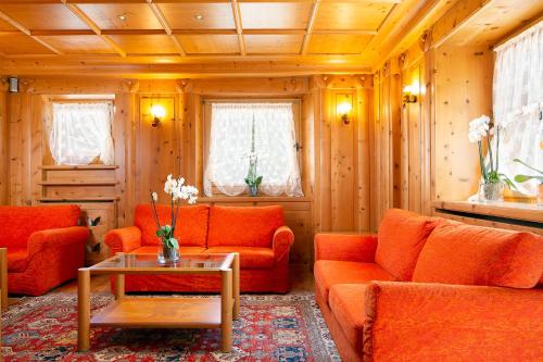 a living room with orange couches and a table at Hotel Natale in Cortina dʼAmpezzo