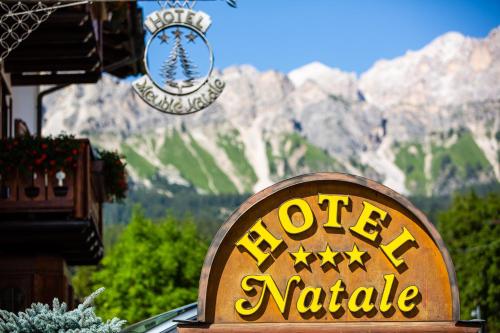 a sign for a hotel with mountains in the background at Hotel Natale in Cortina dʼAmpezzo
