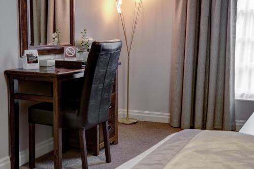a bedroom with a desk with a chair and a mirror at Best Western Plus West Retford Hotel in Retford