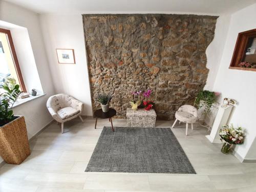 a living room with two chairs and a stone wall at Terry's House in Nuoro