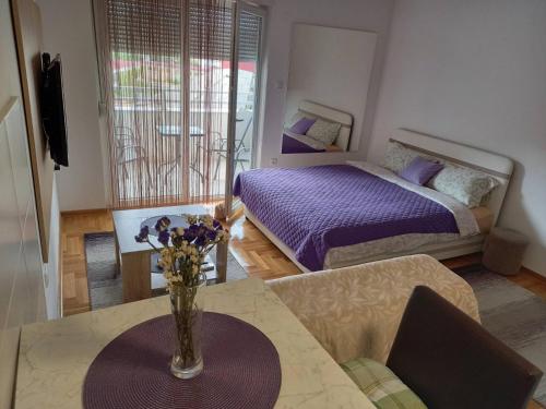 1 dormitorio con 1 cama y un jarrón de flores sobre una mesa en Apartman Magdalena, en Trebinje