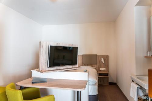 Habitación pequeña con cama y TV. en Gasthaus & Weingut zum Stern, en Sulzfeld am Main