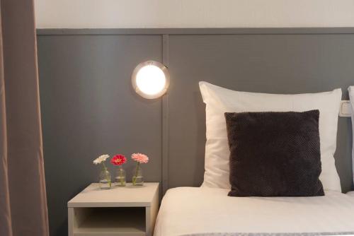 a bed with a black headboard and a table with flowers at Hotel Dupuis in Valkenburg