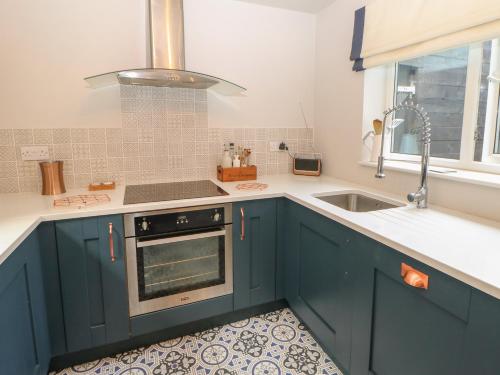 a kitchen with blue cabinets and a sink at 2 Drumrauch Cottages in Yarm