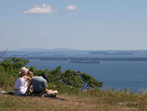 three people sitting on a hill looking at the water at Lord Camden Inn in Camden