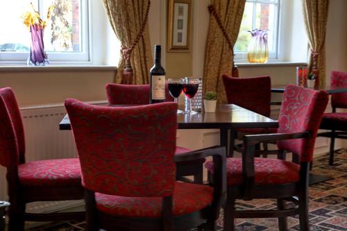 a table with red chairs and a bottle of wine at Best Western Plus West Retford Hotel in Retford