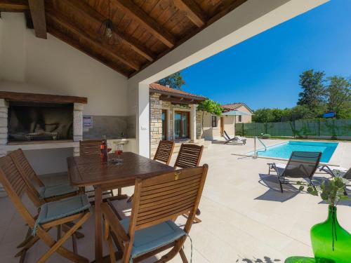 a patio with a wooden table and chairs and a swimming pool at Holiday Home Florens - ROJ469 by Interhome in Sveti Petar u Šumi