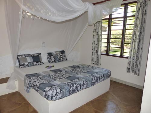 a bedroom with a bed with a canopy at Safina Cottages in Diani Beach