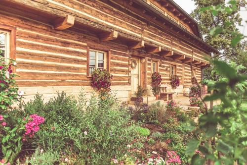 a wooden house with flowers in front of it at Roubenka u Huvarů in Tachov