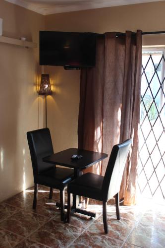 a table and two chairs in a room with a window at 25 on Fitzpatrick in Parow