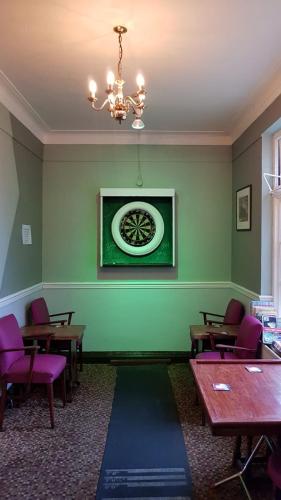a dining room with tables and a clock on the wall at Hour Glass Hotel in London