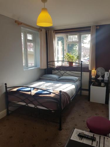 a bedroom with a bed and two windows at Hour Glass Hotel in London