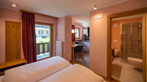 um quarto com uma cama e uma casa de banho com uma janela em Residence Soratru em San Vigilio Di Marebbe