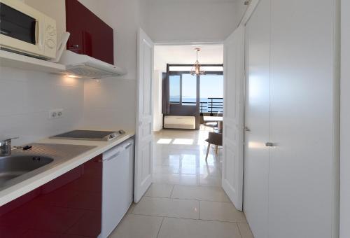 a white kitchen with a sink and a microwave at Résidence Les Calanques in Ajaccio