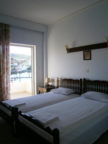 a bedroom with a large bed and a large window at Daskalio Beach Hotel in Keratea