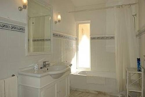 a white bathroom with a sink and a tub and a window at Villa Quadradinhos 46Q Located close to the tennis courts and just 100m from the famous Restaurant in Vale do Lobo