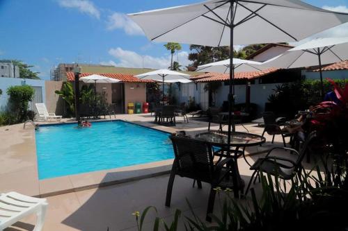 a pool with tables and chairs and umbrellas at Pousada Angra do Porto in Porto De Galinhas