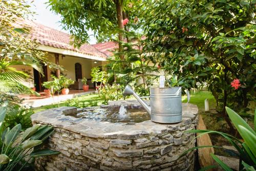 a stone fountain with a bucket in a garden at Hotel Flor De Sarta in León
