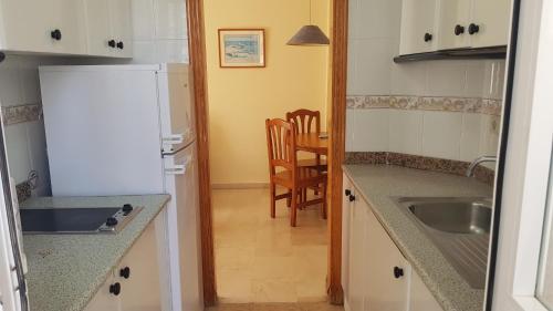a kitchen with a white refrigerator and a table at Torres Gardens-Fincas Benidorm in Benidorm