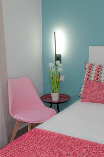 a bedroom with a pink chair and a table at ABAL Apartments - Barrio in Alicante