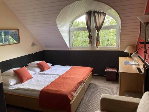 - une chambre avec un grand lit et une fenêtre cintrée dans l'établissement Berg Toboz Panzió, à Pécs