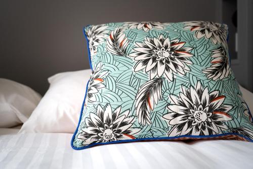 a pillow sitting on a bed with a floral pillow at Les Jardins de Joséphine - Le Manoir in Évreux