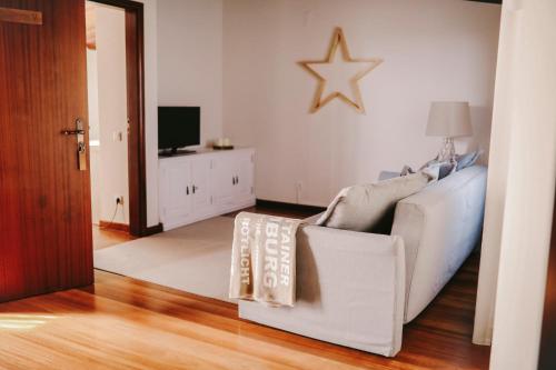 a living room with a white couch and a television at Vila Louro in Santa Cruz