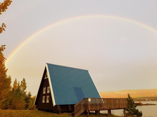 a barn with a blue roof with a rainbow in the background at Ormurinn Cottages in Egilsstadir