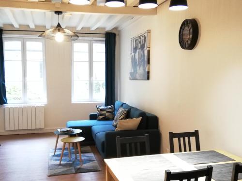 un salon avec un canapé bleu et une table dans l'établissement Welk'Home Loft Rouen CHU - Coeur Historique, à Rouen