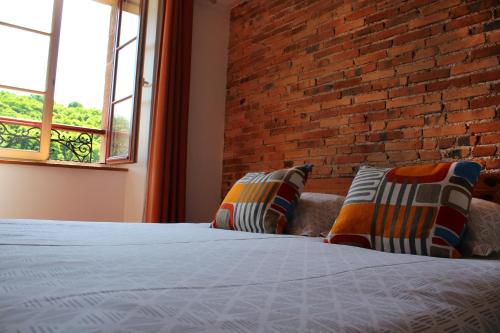 a bedroom with a brick wall and a bed with pillows at Moulin Pont Vieux Chambres d'hôtes in Mortagne-sur-Sèvre