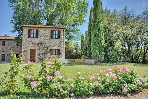a stone house with a garden with flowers at I Casali Della Ghisleria in Ospedalicchio