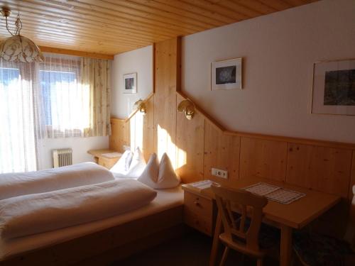 a bedroom with a bed and a desk and a window at Berggasthaus Trojen in Sankt Jakob in Defereggen