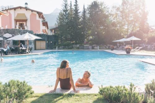 two women sitting next to a swimming pool at Wellnesshotel ...liebes Rot-Flüh in Haldensee