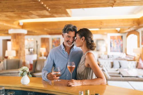 a man and a woman standing at a bar with wine glasses at Wellnesshotel ...liebes Rot-Flüh in Haldensee
