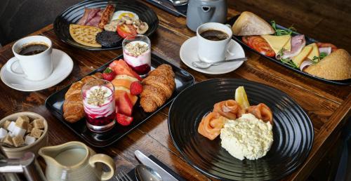 a wooden table with plates of food and cups of coffee at Bosville Hotel in Portree